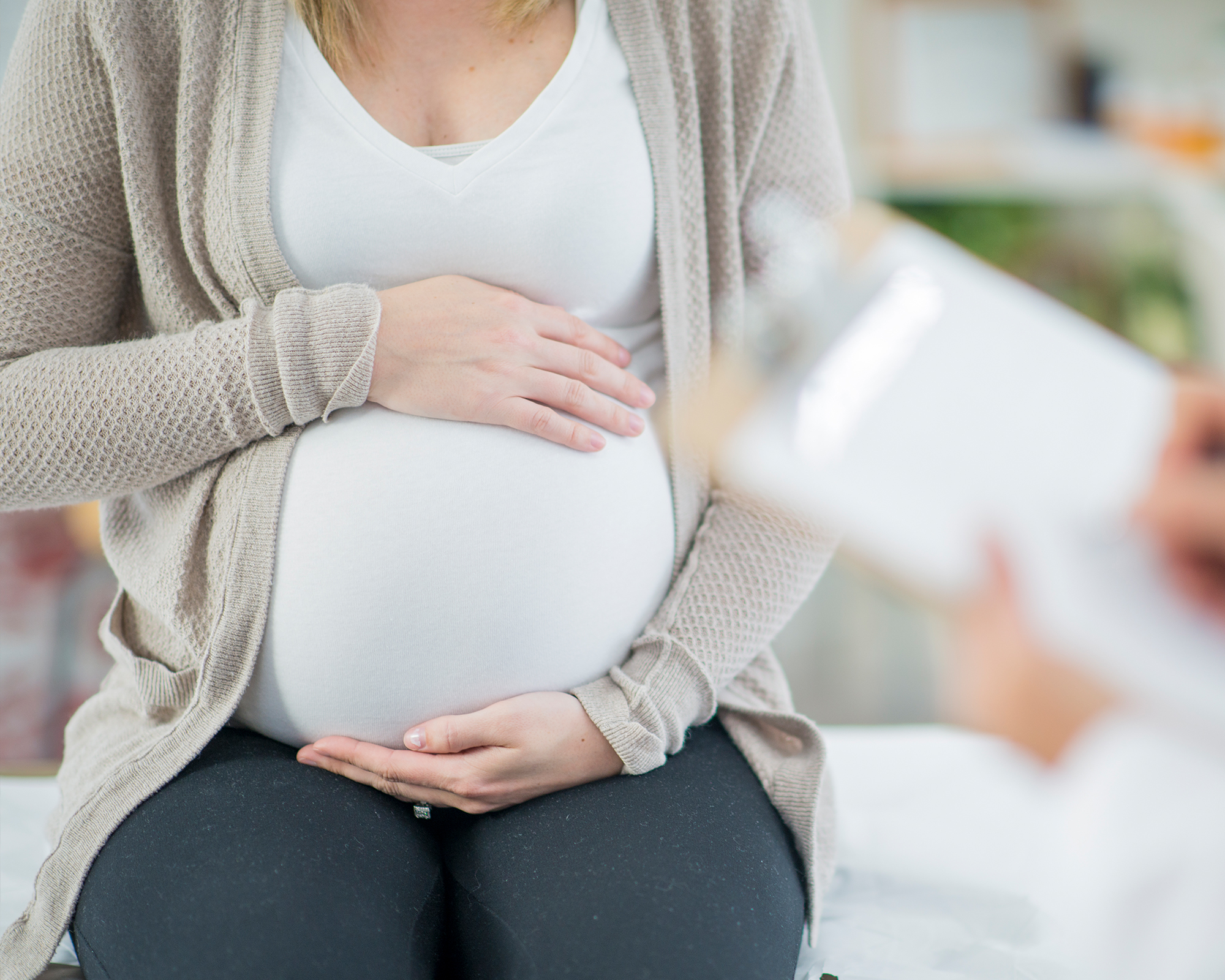 Ein Schwangerschaftsbauch der von den Händen der Mutter schützend gehalten wird